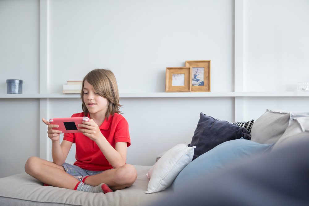 Kid sitting on bed playing games on a device